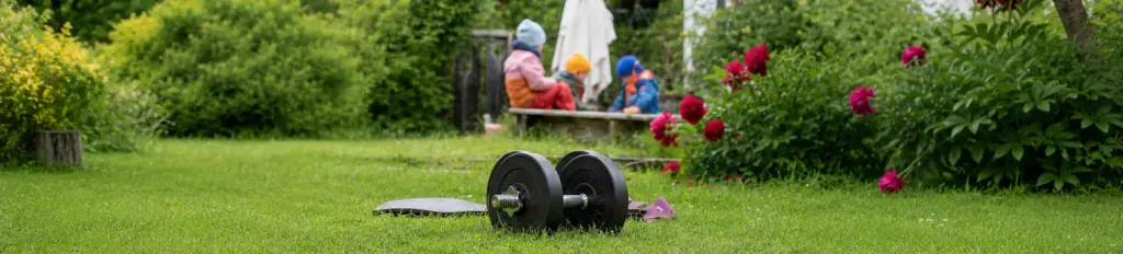 Eine Hantel in einem Garten. Im Hintergrund spielen Kinder